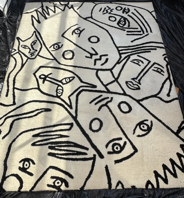 Gereinigd licht tapijt met een zwart-wit dessin van getekende gezichten