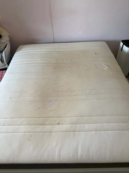 Wit matras vóór reiniging, met meerdere zichtbare vlekken en verkleuringen