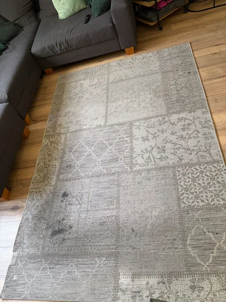 Lichtgrijs patchwork vloerkleed vóór reiniging, met donkere vlekken en plaatselijke vervuiling